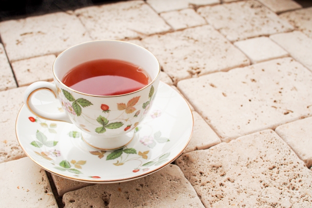 白い石畳の上に置かれた、紅茶が入った花柄のティーカップとソーサー